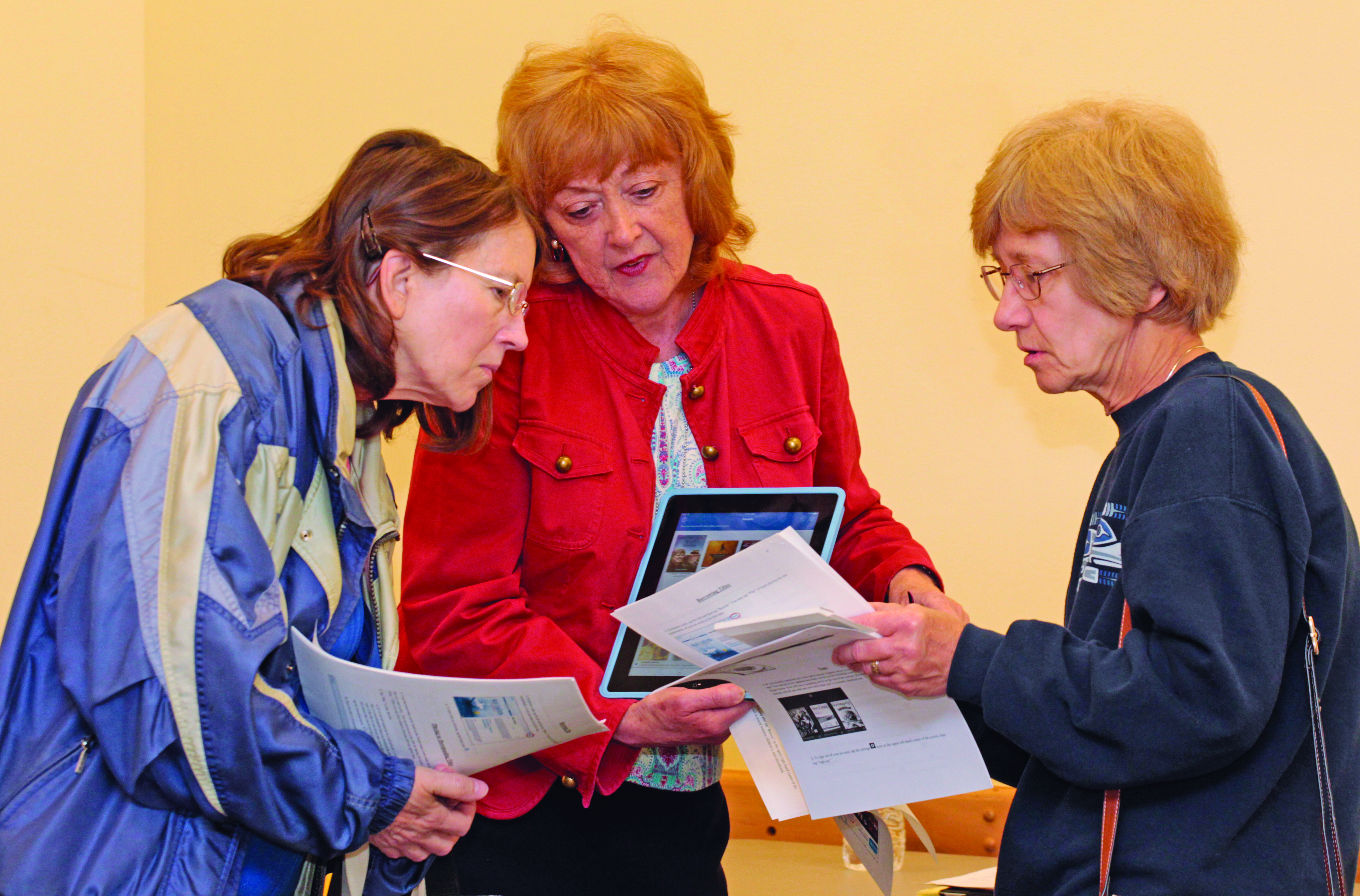 Adult Services Librarian Karen Shalt demonstrates the “Hoopla” app to Marcia Kline and Ginny Zajac. Photo by Chuck LeClaire